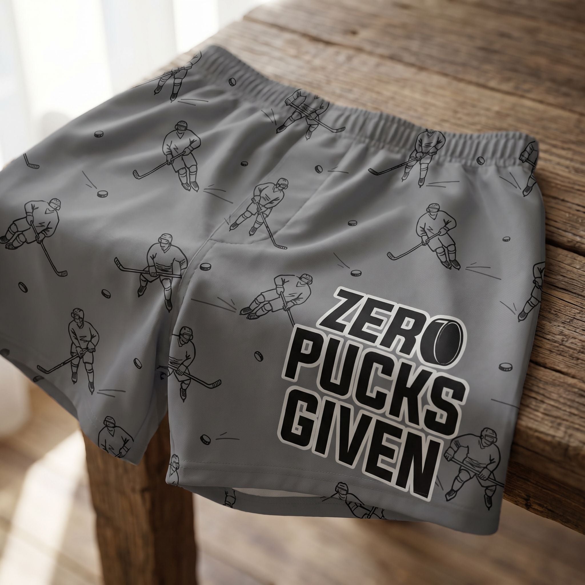 Close-up of Zero Pucks Given boxer shorts with hockey pattern on textured wood surface, highlighting fabric details and waistband.