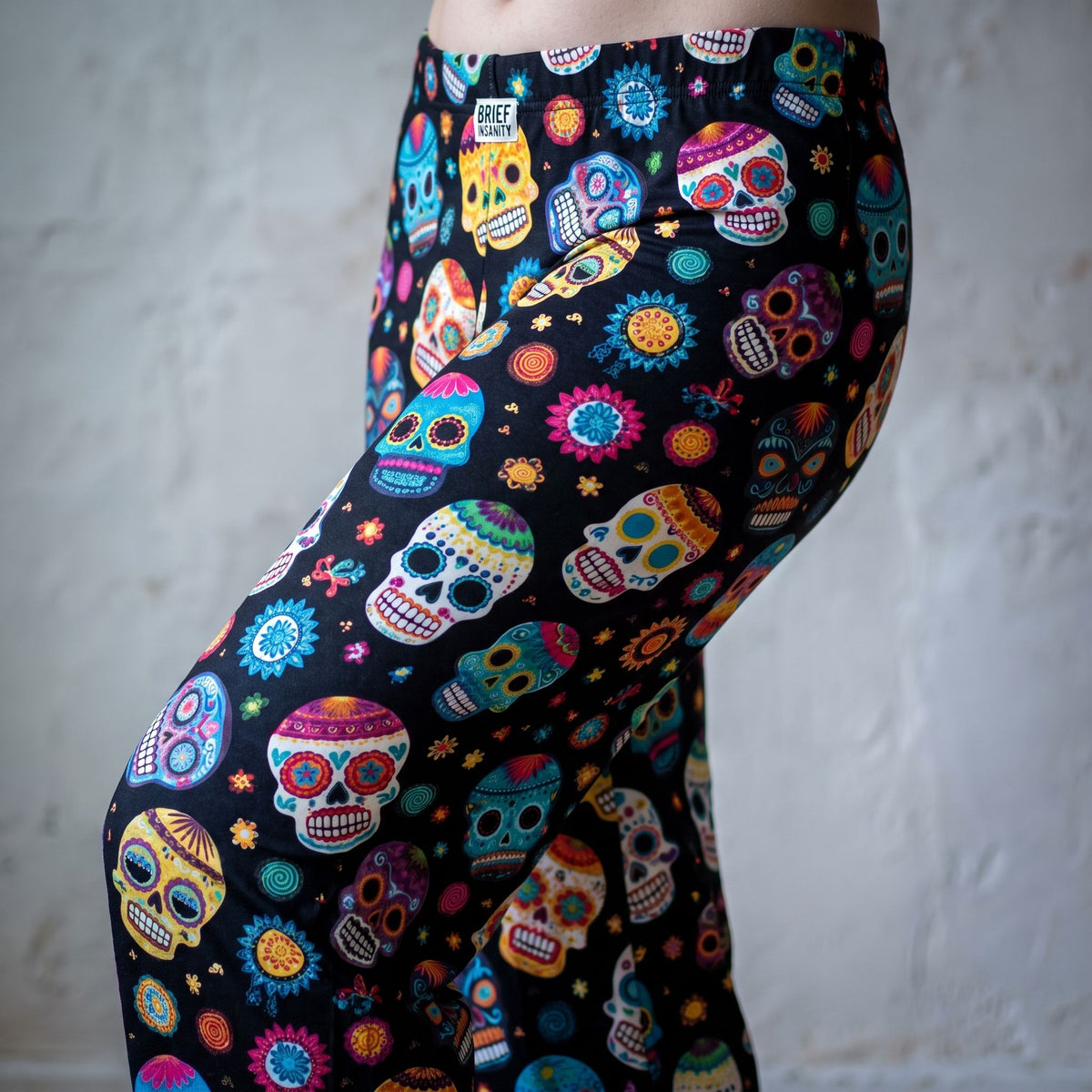 Close-up view of fabric detailing on Day of the Dead skull lounge pants with colorful floral motifs and comfortable drape.