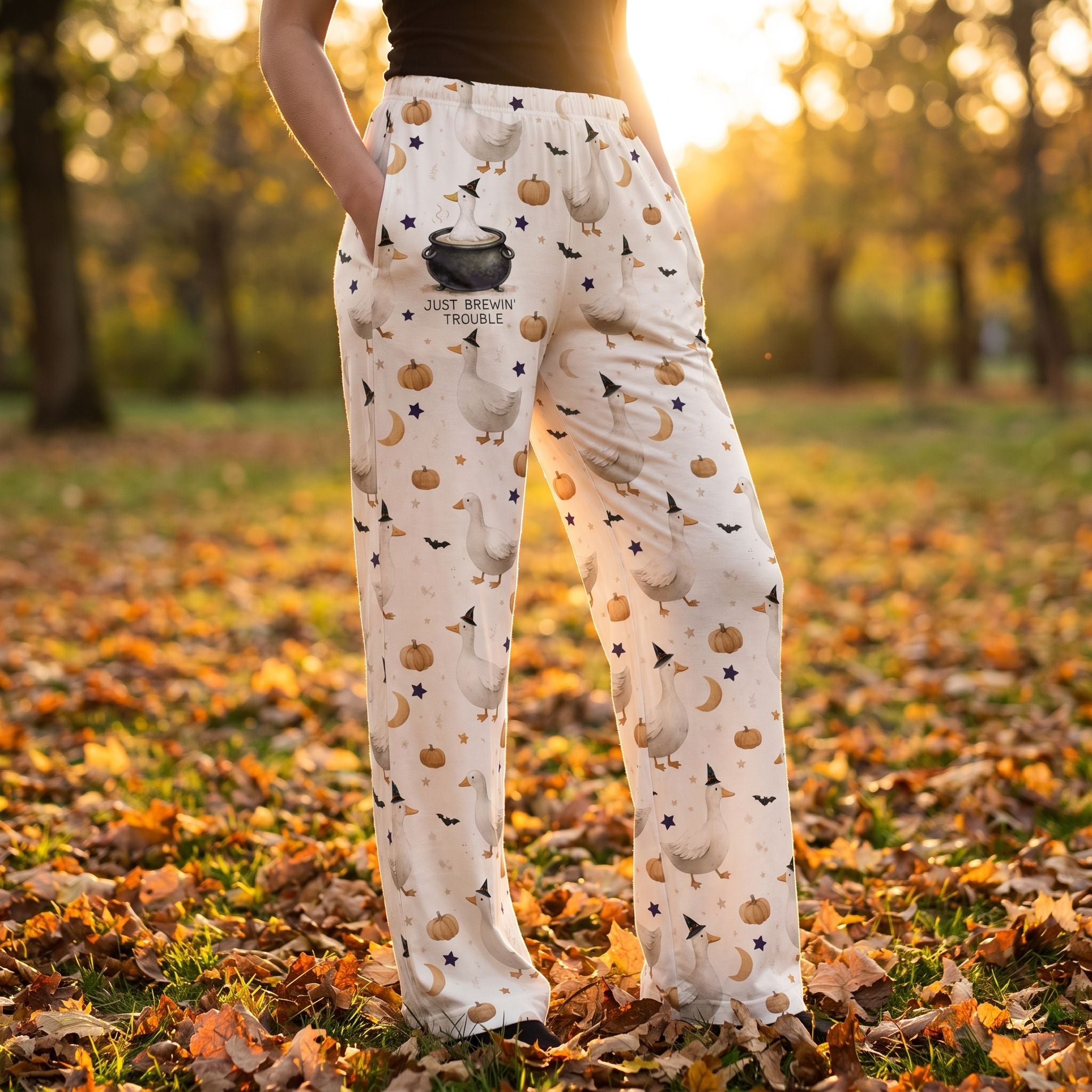 Model wearing Brewin' Trouble & Gooses lounge pants outdoors during golden hour, showcasing relaxed fit, whimsical Halloween print, and cozy style.