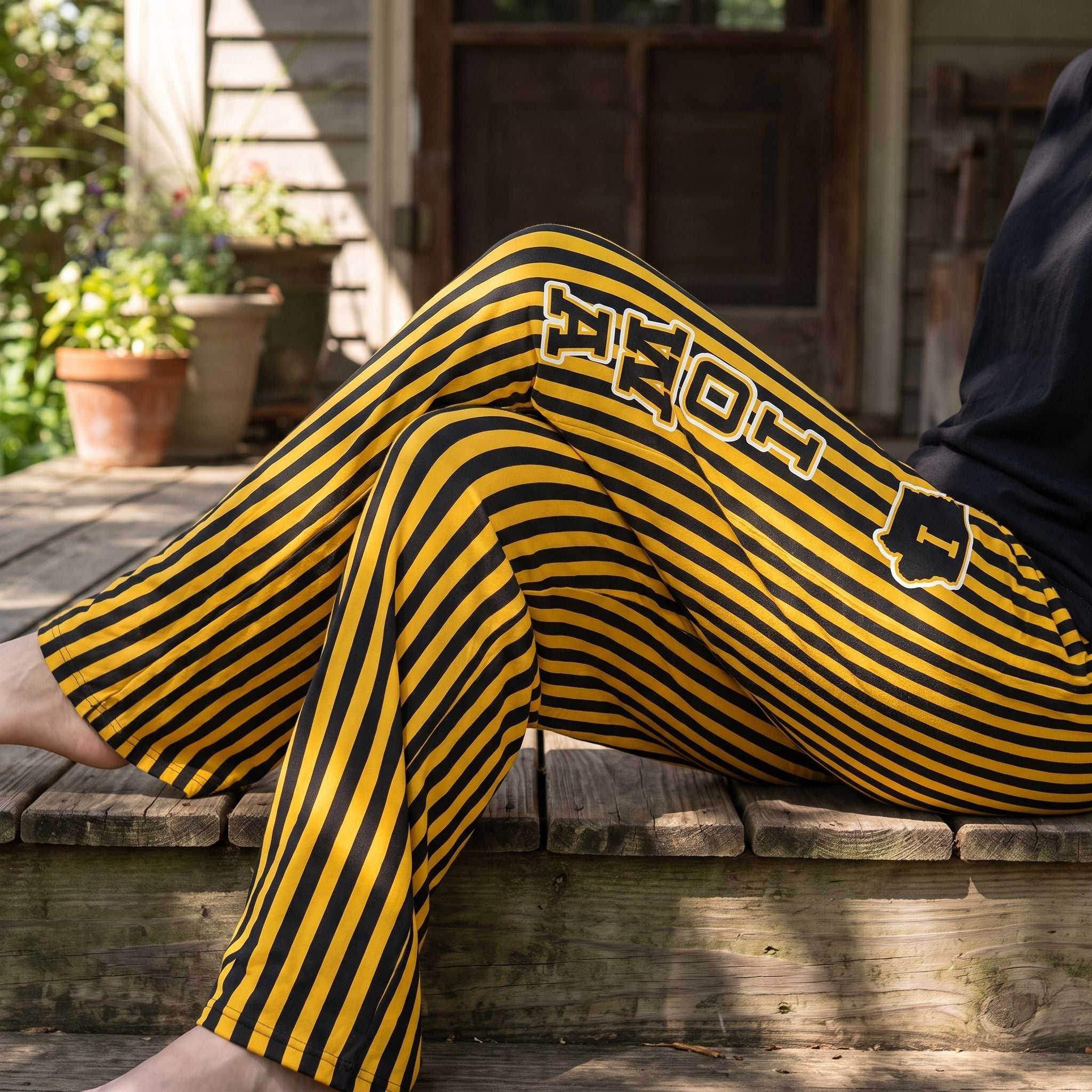 Person sitting outdoors on porch wearing Iowa striped pajama pants, showcasing casual style and comfortable fabric.