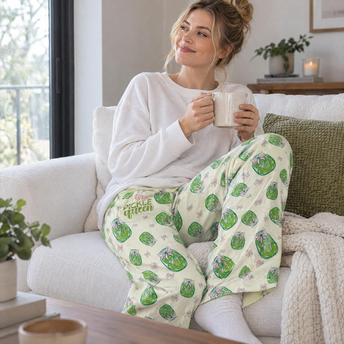 Person relaxing on a plush white sofa wearing patterned lounge pants with a pickle jar print.