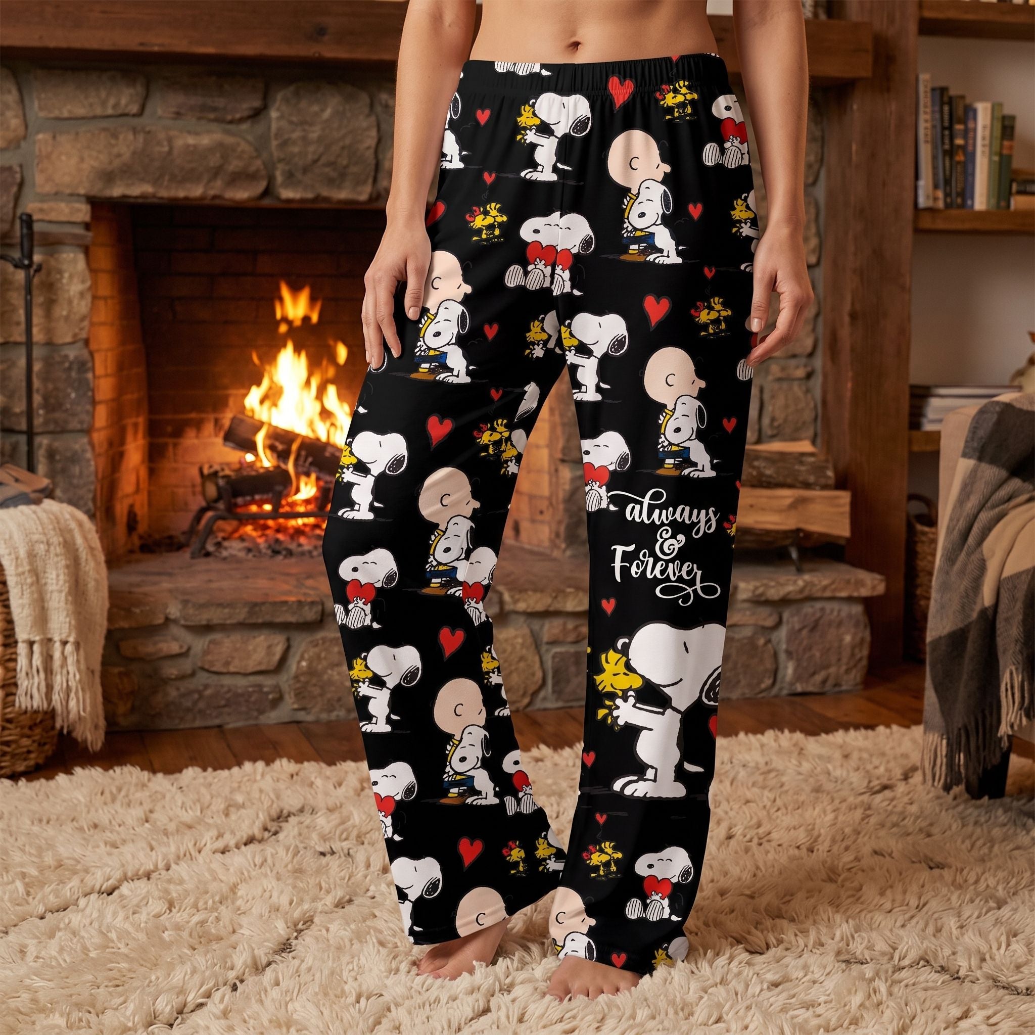 Full-body view of a woman in vibrant Snoopy-themed lounge pants, standing comfortably in a cozy home with fireplace and plush rug.
