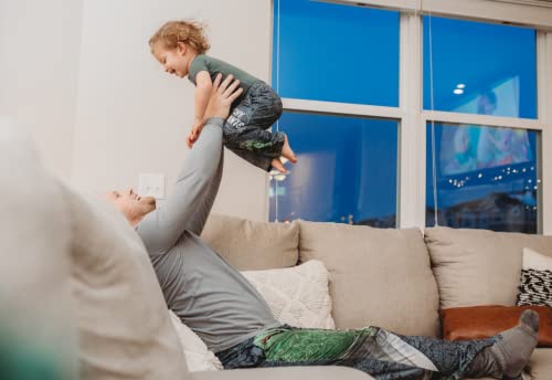 Image of dad model wearing Sesame Street Oscar The Grouch pajama lounge pants lifting up and playing with daughter model who's also wearing Sesame Street Oscar The Grouch pajama lounge pants (kids version)