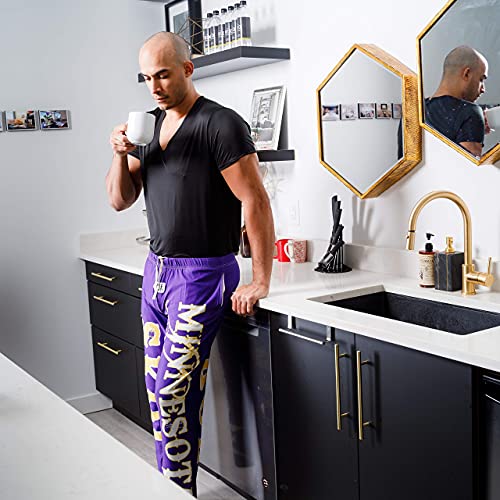 Image of male model drinking coffee in kitchen wearing SKOL pajama lounge pants