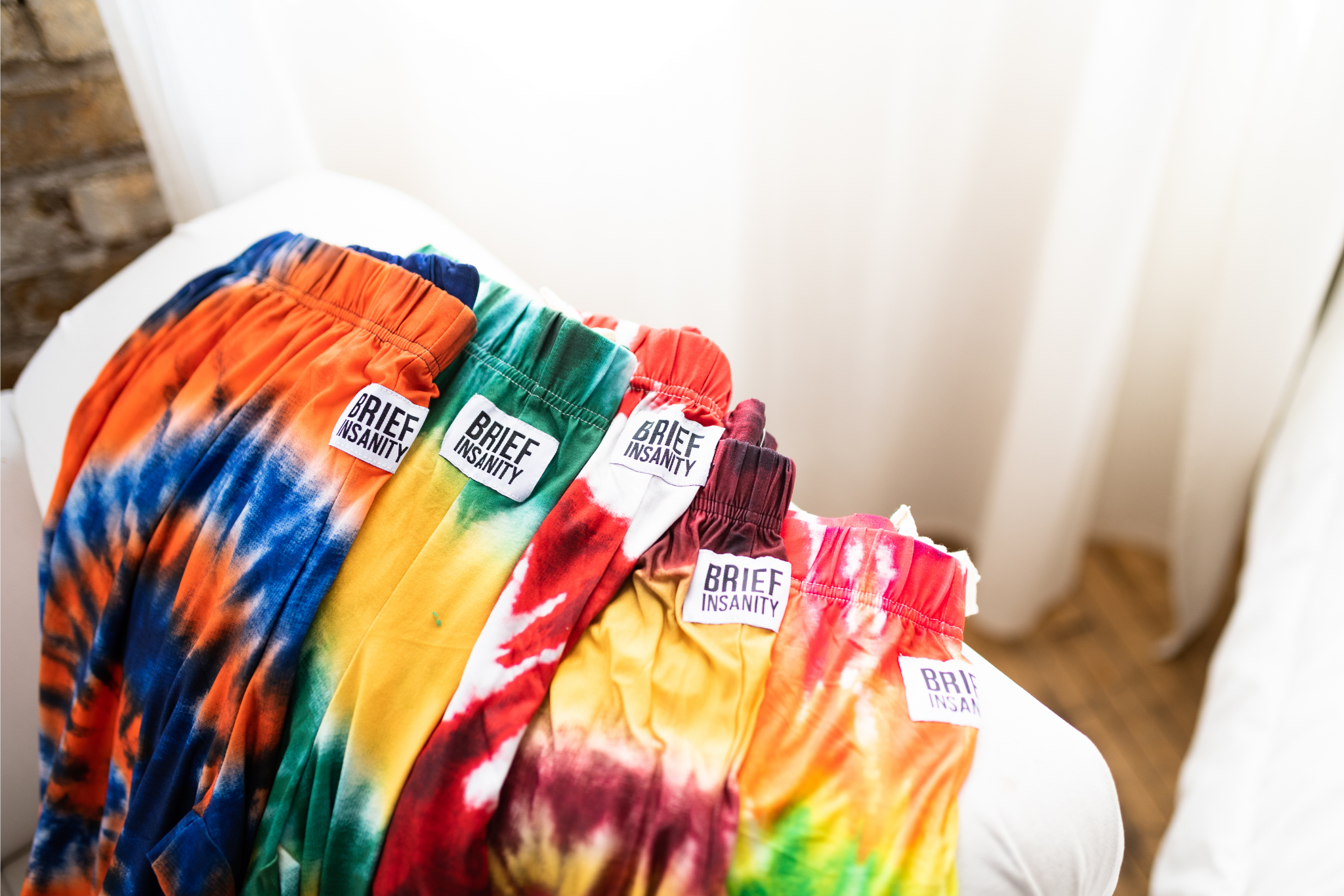 Image of a group of lounge pants laid out on arm of couch