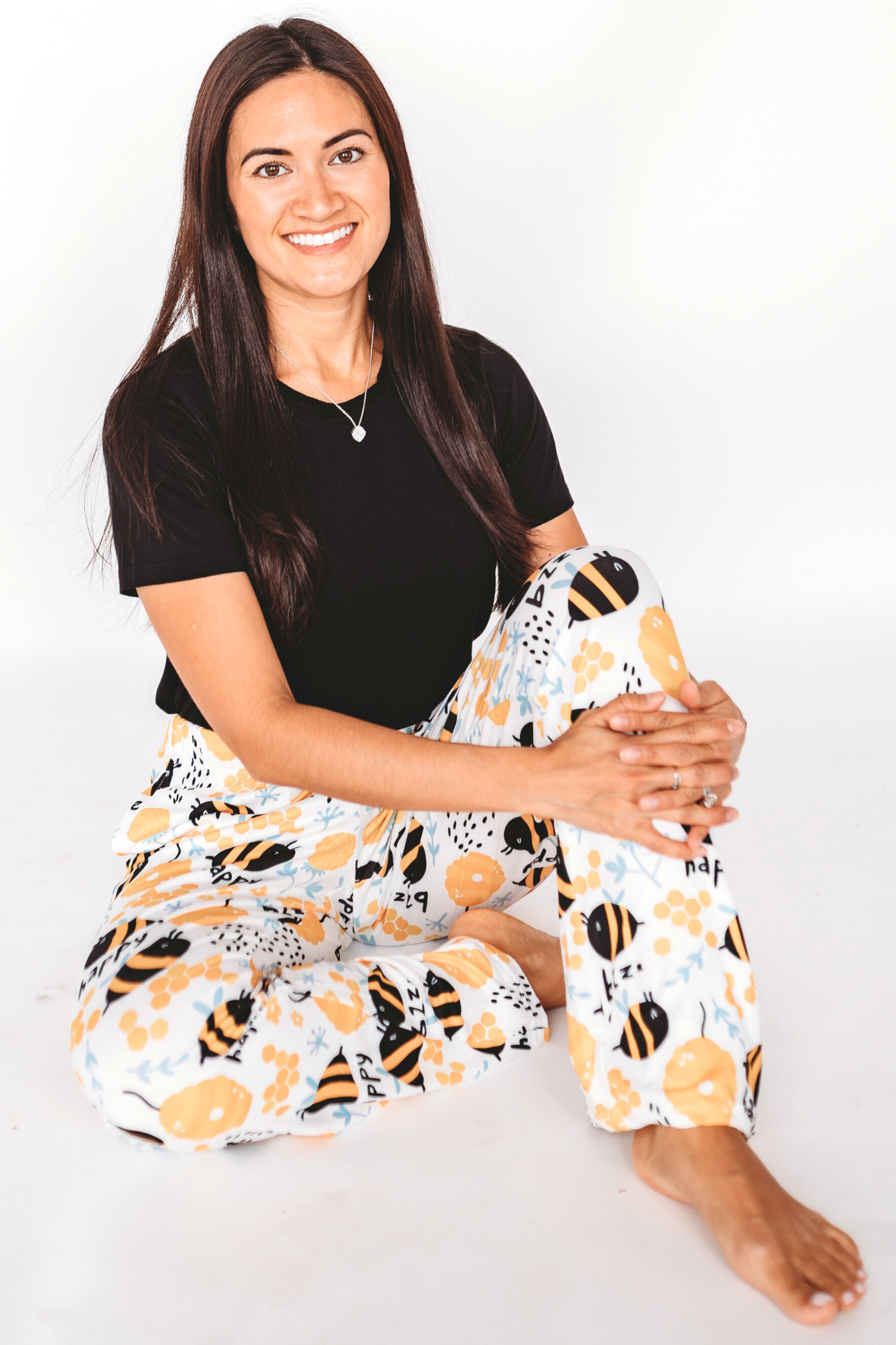 Image of model sitting on the floor wearing Honey Bee pajama lounge pants front view (white background)