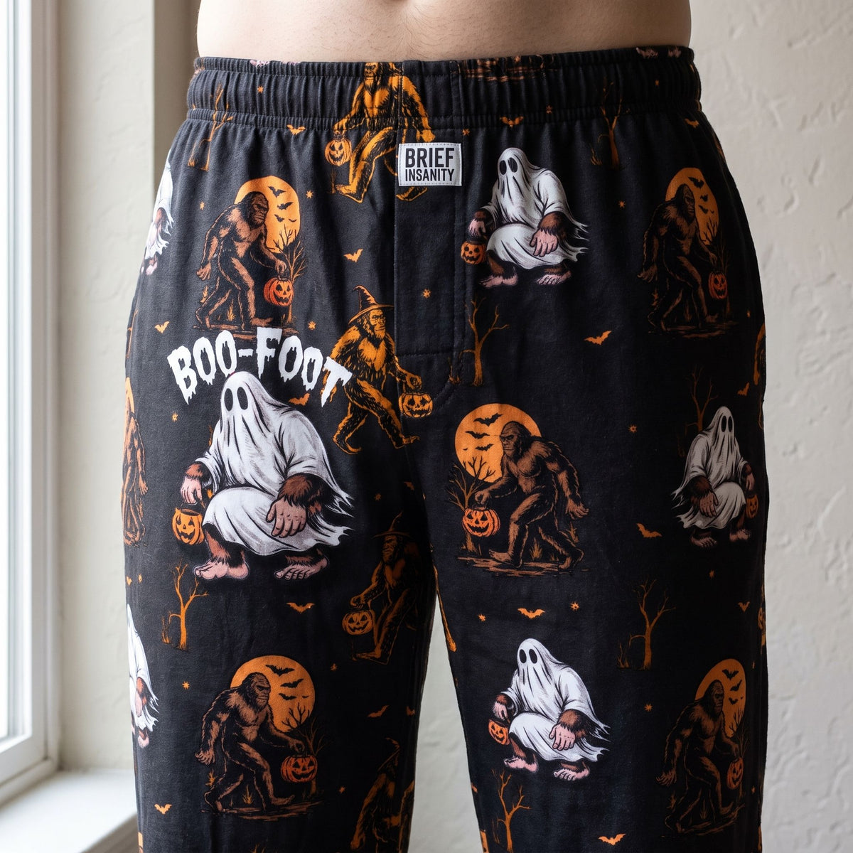 Close-up of Boofoot Orange Halloween Lounge Pants showcasing pumpkin and ghost pattern on a mannequin