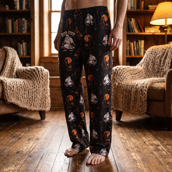 Full-body view of Boofoot Orange Halloween Lounge Pants worn by a person in a cozy rustic room with warm lighting