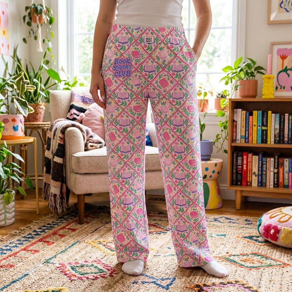 Model standing in a vibrant, colorful living room wearing Book Lover Club Lounge Pants, surrounded by plants and playful decor.