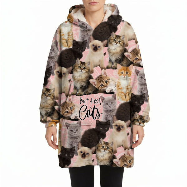 Model wearing an oversized cat blanket hoodie featuring adorable cat graphics against a white background.