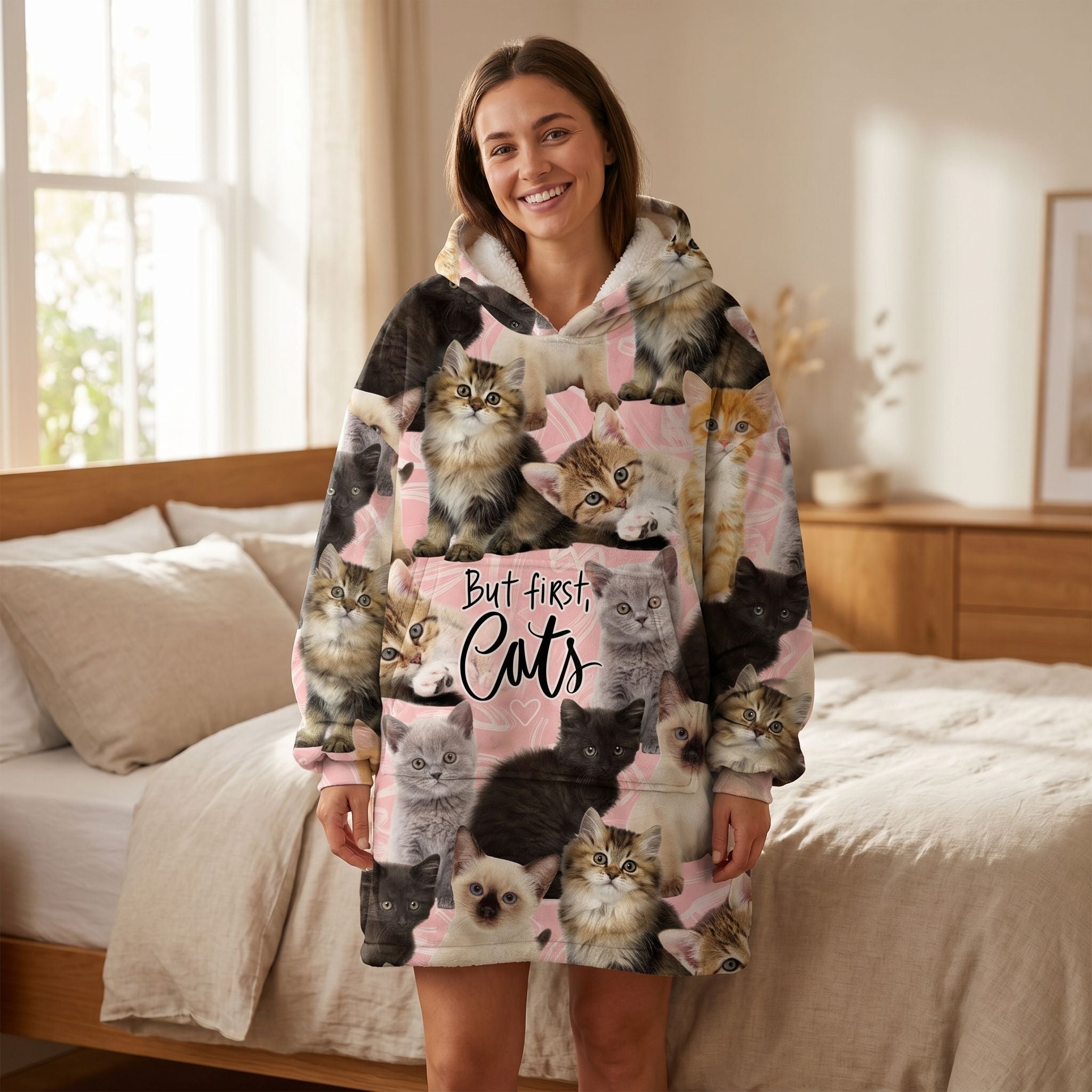 Woman wearing an oversized blanket hoodie with cat-themed design, cozy bedroom setting, showcasing the plush fleece exterior and sherpa lining.