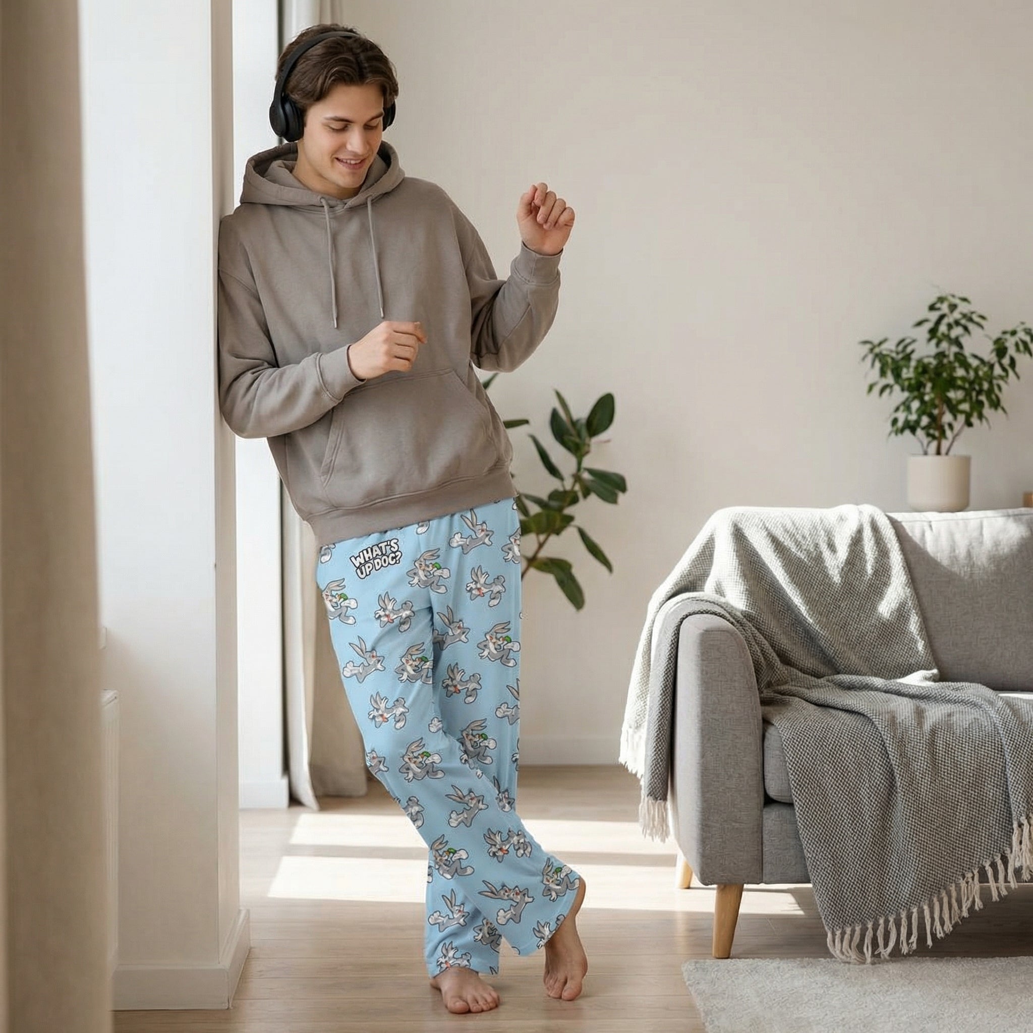 Person in Bugs Bunny lounge pants, standing or leaning with headphones in a modern room, relaxed and stylish.