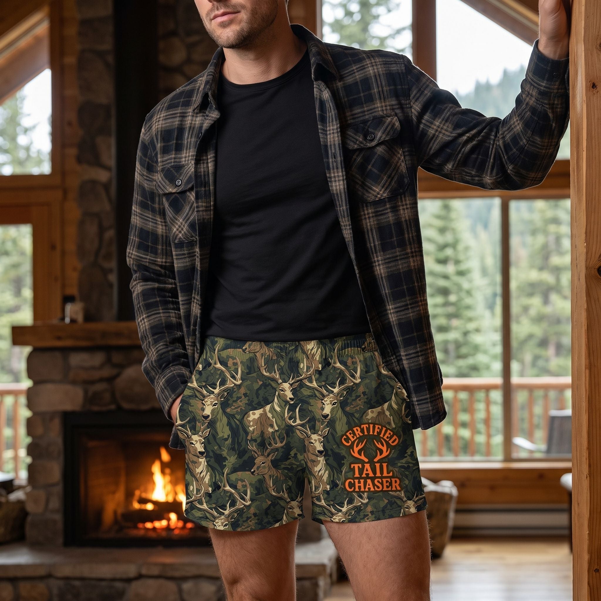 Man in a mountain lodge wearing camouflage deer boxers with flannel shirt and black T-shirt, fireplace and pine trees view.