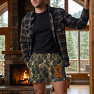Man in a mountain lodge wearing camouflage deer boxers with flannel shirt and black T-shirt, fireplace and pine trees view.