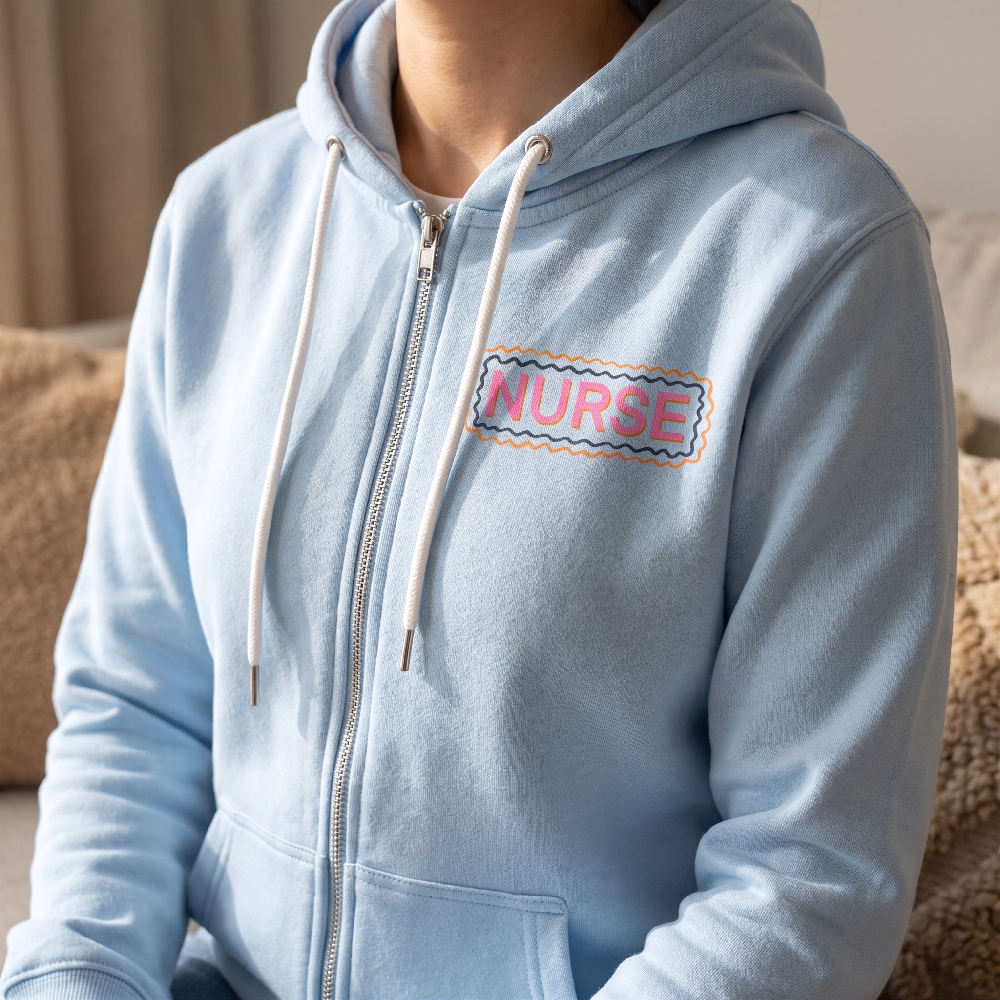 Close-up of Nurse Doodles Zip Up Hoodie highlighting the 'NURSE' graphic on the chest in natural light.