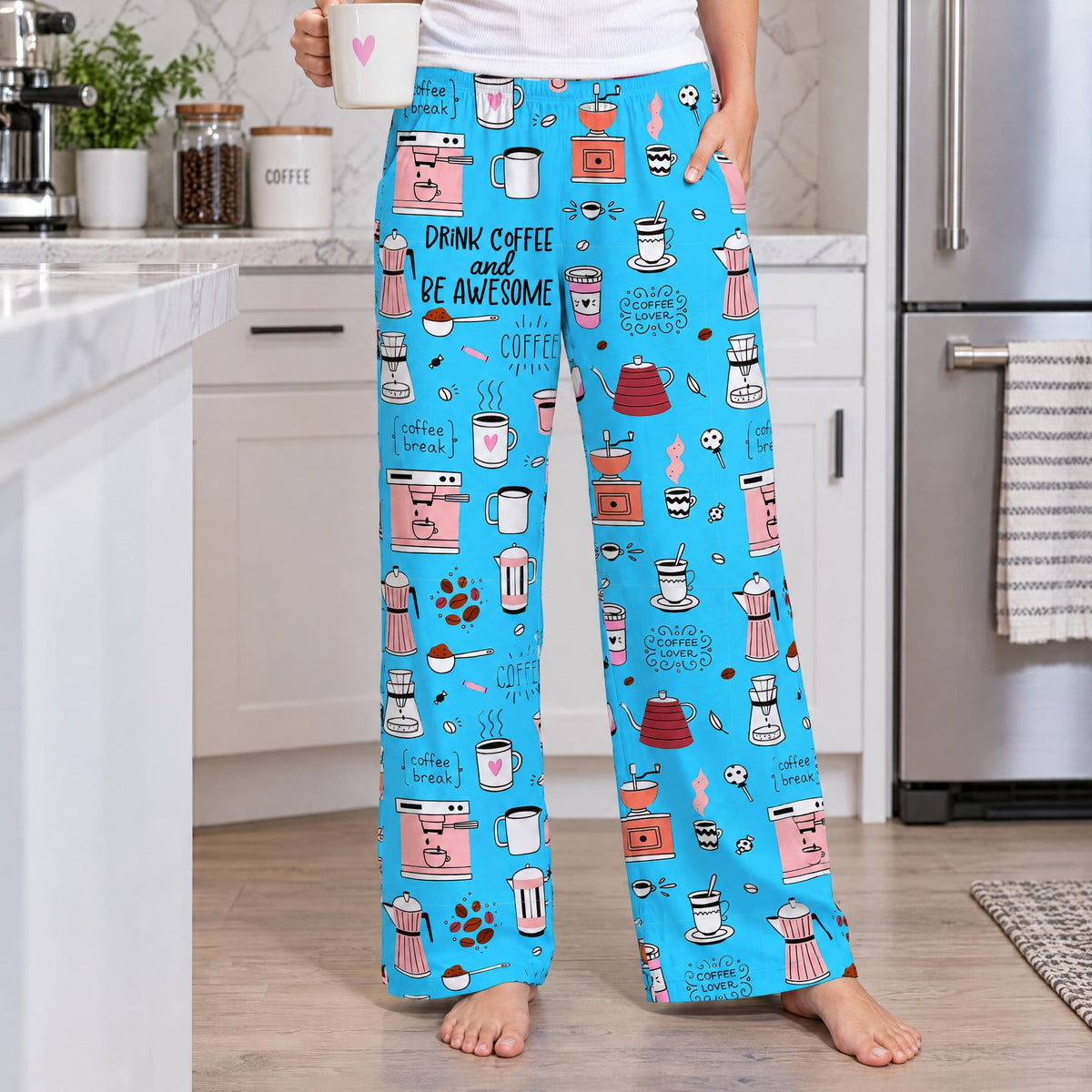 Detailed close-up of blue lounge pants featuring a pattern of coffee mugs, beans, and makers in a kitchen setting.