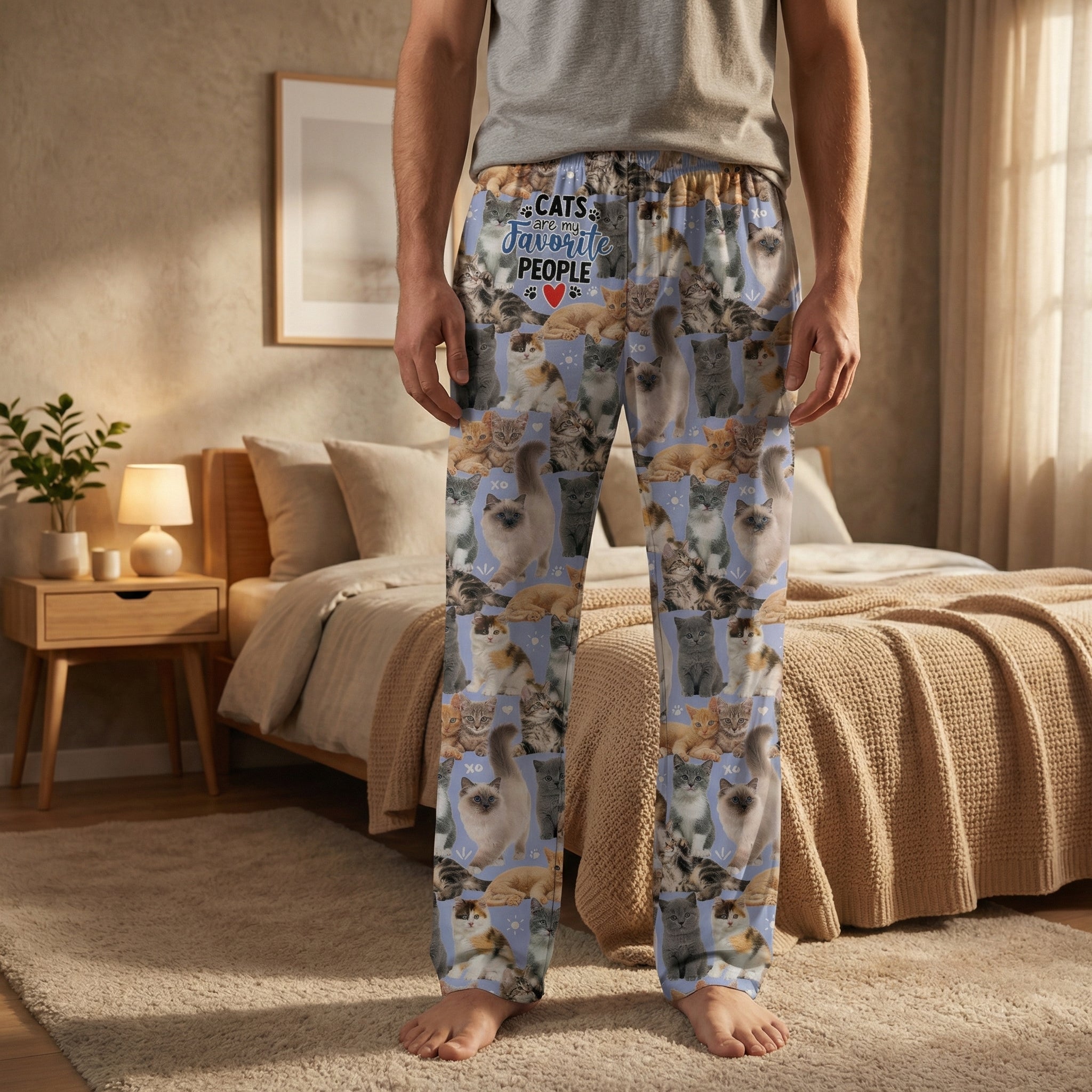 Male model wearing Cats Favorite People Lounge Pants standing in a warm lit bedroom with a neatly made bed and minimal decor, emphasizing comfort and relaxed style.