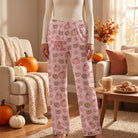 Female model wearing Pumpkin Spice Dreams lounge pants in cozy autumn home setting with pumpkins and fall foliage.