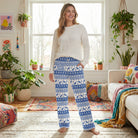 Model wearing I'd Rather Be Skiing lounge pants in a colorful living room with plants and playful decor, highlighting the Nordic-inspired winter pattern.