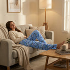Female model wearing Blue Hydrangea Lounge Pants, relaxing on a modern couch in a cozy living room.