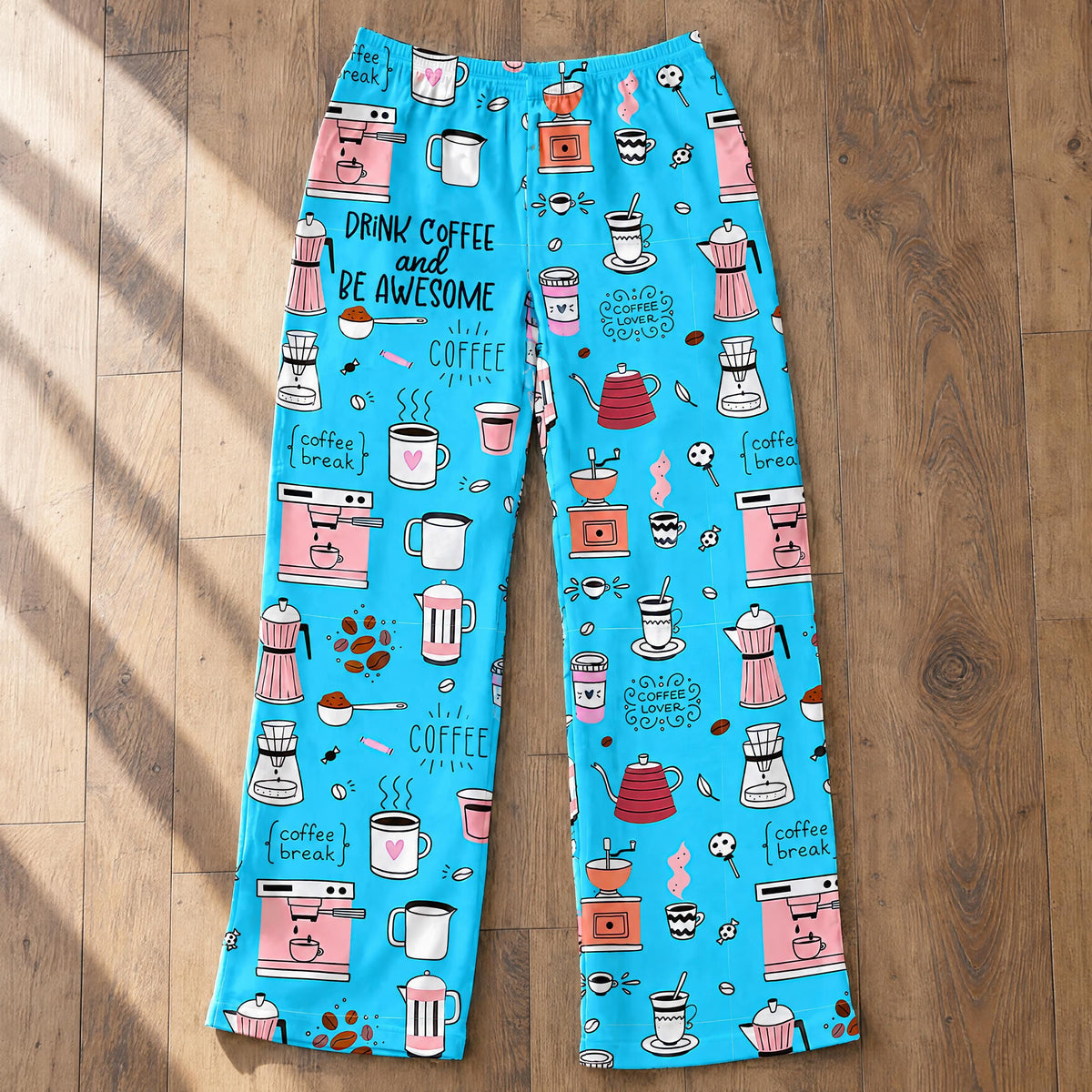 Flat lay view of blue coffee themed lounge pants showing the full pattern of beans and cups on a hardwood floor.