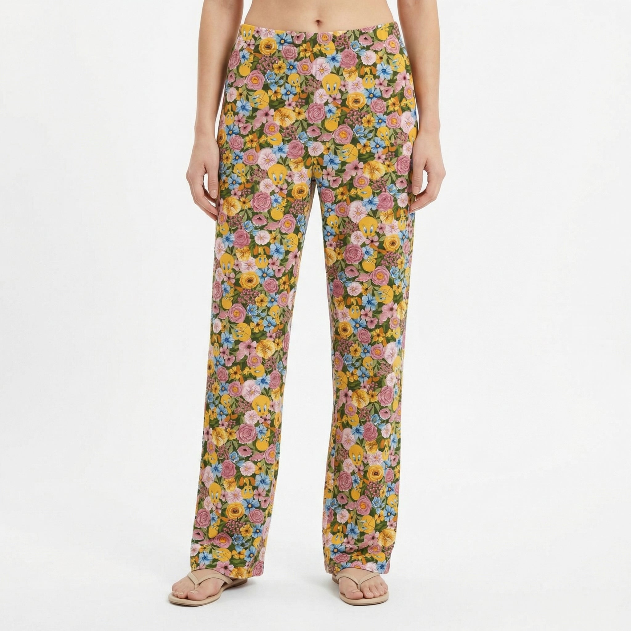 Model wearing floral Tweety lounge pants featuring vibrant garden-inspired print with Tweety accents, set against a white background for product focus.