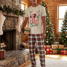 Full-body shot of a model in a festive shirt in a rustic living room with holiday gifts and fireplace, emphasizing comfort and holiday spirit
