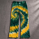 Close up of wide leg lounge pants featuring a vibrant green and gold spiral tie dye pattern on lightweight knit fabric.