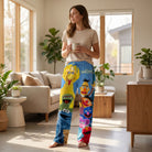 Female model in Sesame Street lounge pants, in a bright living room holding a coffee mug and relaxing.