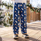 Child wearing kids Christmas blue milk and cookies lounge pants outdoors on a sunny winter day with festive background.
