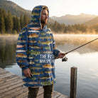 Realistic outdoor scene of a male model wearing the Fish Whisperer blanket hoodie on a lake dock at sunrise, holding a fishing rod.