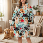 Lifestyle shot of woman in dog-themed blanket hoodie in living room with relaxed dog nearby, natural warm lighting.