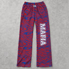 Mafia zebra print lounge pants in blue and red laid flat on a gray concrete surface showing knit fabric and elastic waistband.