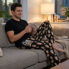 Male model wearing Easy Tiger Lounge Pants on a couch, holding a game controller in a cozy, modern living room.