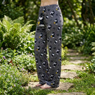 Female model outdoors in garden wearing Detective Snoopy Lounge Pants, daylight highlighting playful print and fabric micro-texture.