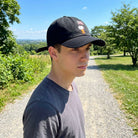 Person wearing Snoopy space embroidered cap outdoors under bright summer sunlight, showcasing fit and design.