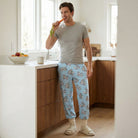 Individual standing in kitchen wearing Bugs Bunny lounge pants, mid-motion with a snack, casual and playful scene.