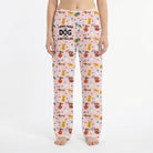 Young woman in playful living room wearing vibrant dog print lounge pants, surrounded by decor and plants.