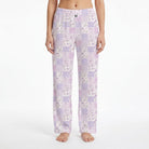 Model wearing purple floral lounge pants with plaid accents, showing vibrant colors and fabric details against a white background.