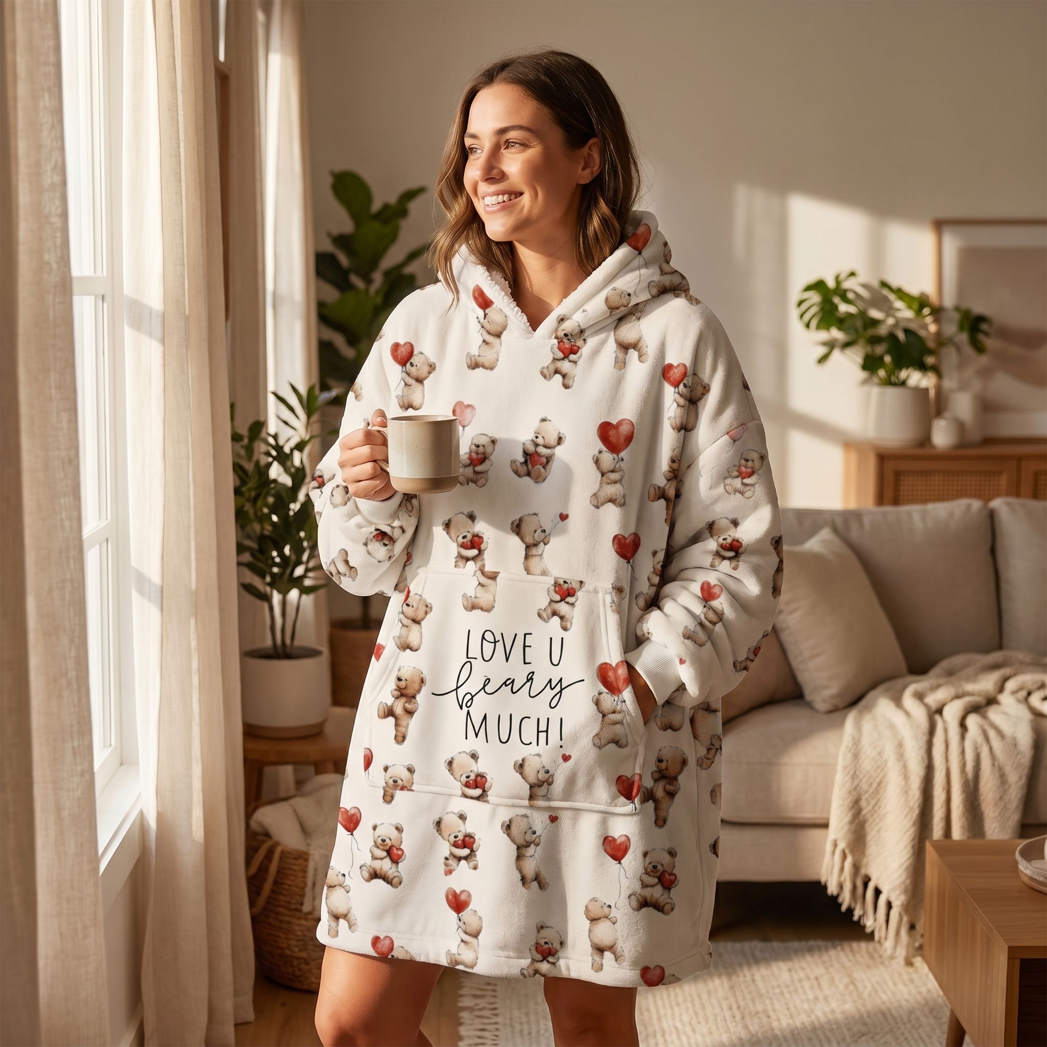 Woman standing with coffee mug in living room wearing Love You Berry Much blanket hoodie with teddy bears.