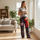 Relaxed female model in Sesame Street Elmo lounge pants in a bright living room with natural sunlight and home decor.