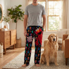 Male model wearing Sesame Street Elmo lounge pants standing next to a dog in a bright, cozy living room with natural light.