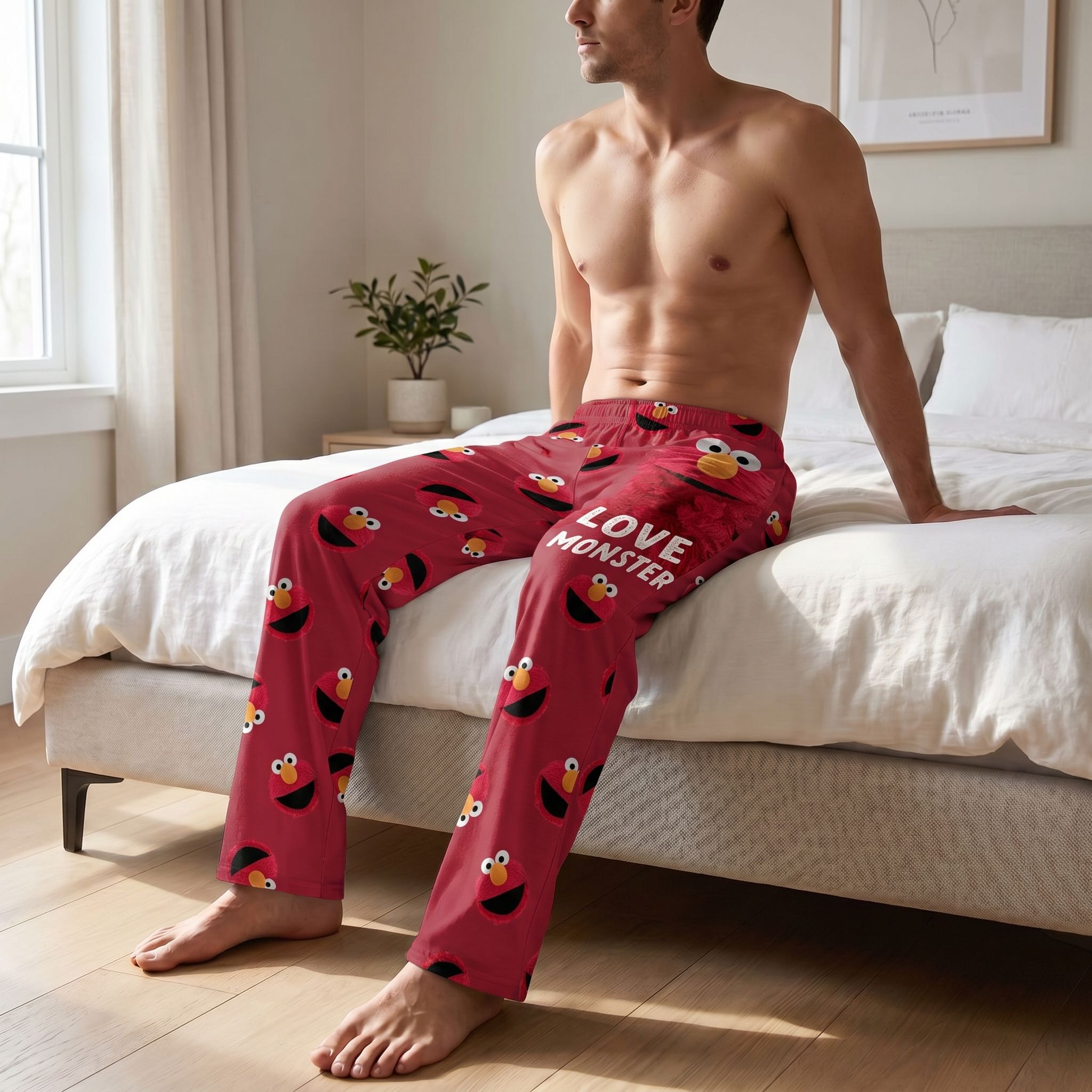 Person relaxing in Sesame Street Elmo Love Monster lounge pants in a playful, colorful pop art style with bold graphics.