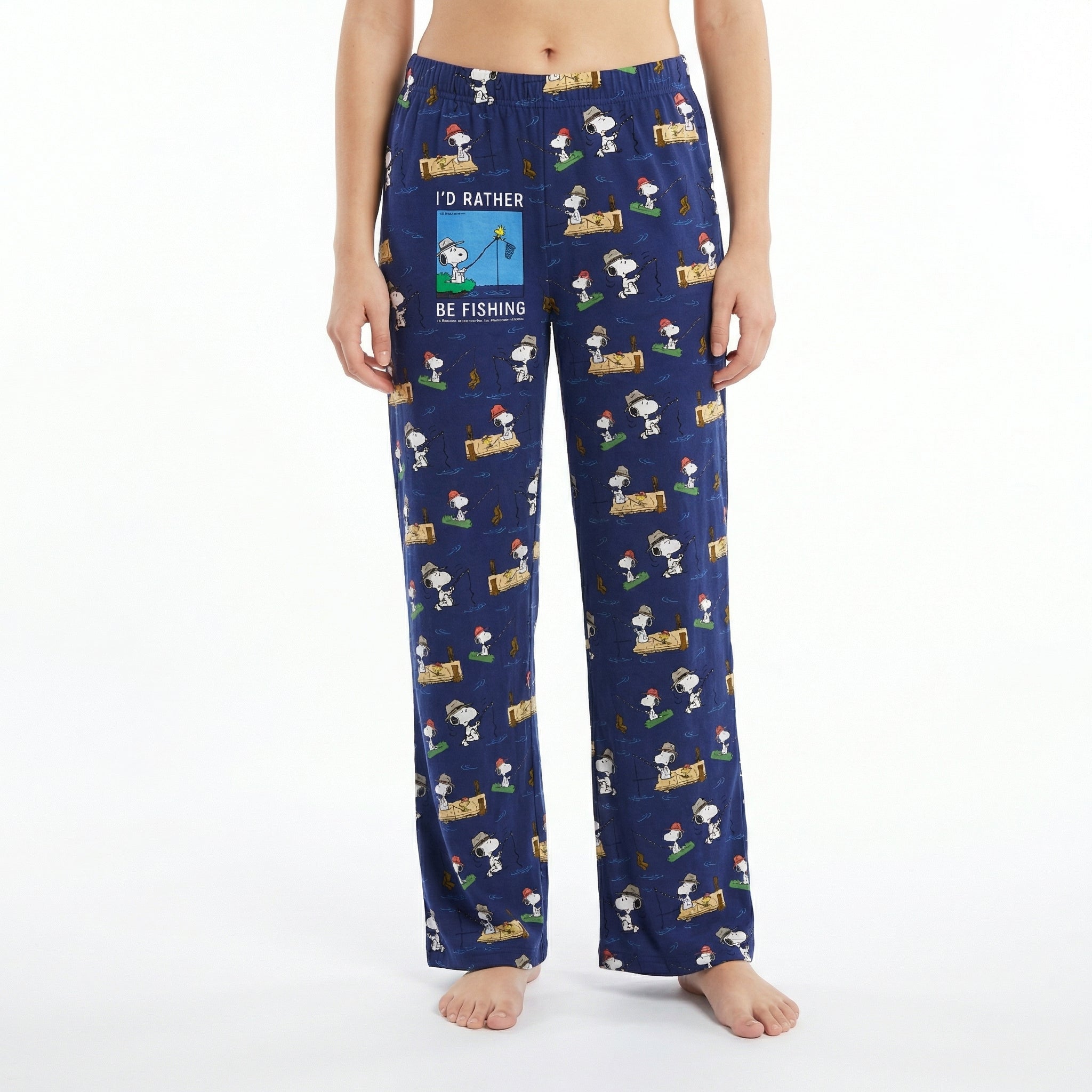 Young female model wearing Snoopy fishing lounge pants with vivid print on white background.