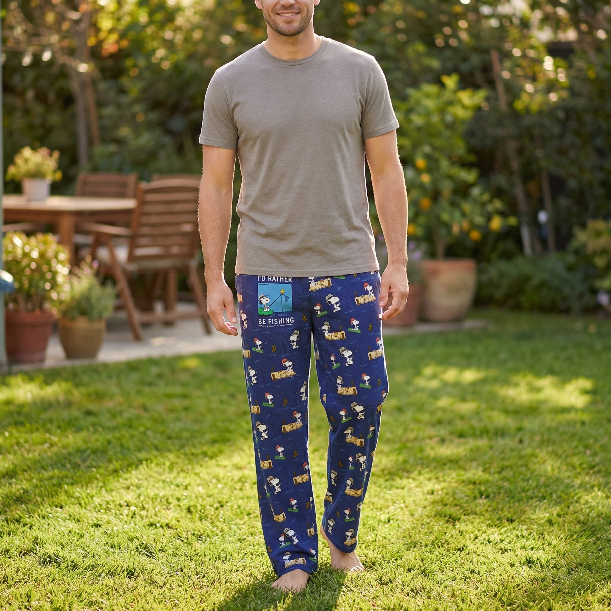Male model wearing Snoopy fishing lounge pants in a sunny backyard, showcasing relaxed fit and playful Snoopy print.
