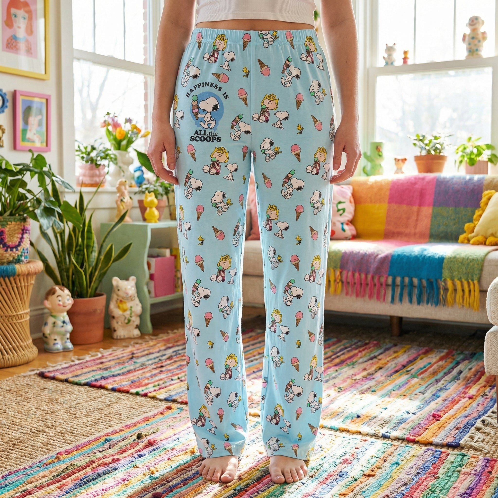Young female model wearing Snoopy ice cream lounge pants cropped from waist to ankles on white background.