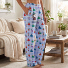 Full-body view of a model relaxed in Snoopy lounge pants in a cozy living room with warm lighting and casual pose.