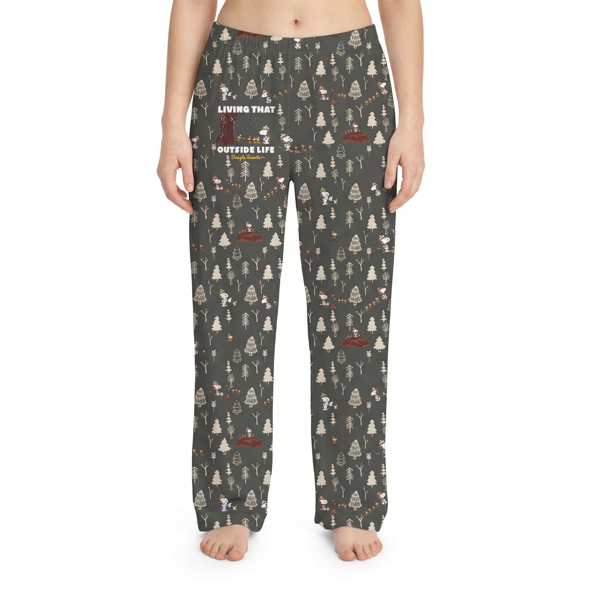 Studio shot of Snoopy Outside Life lounge pants on a female model against white background, emphasizing the woodland print and fabric texture.