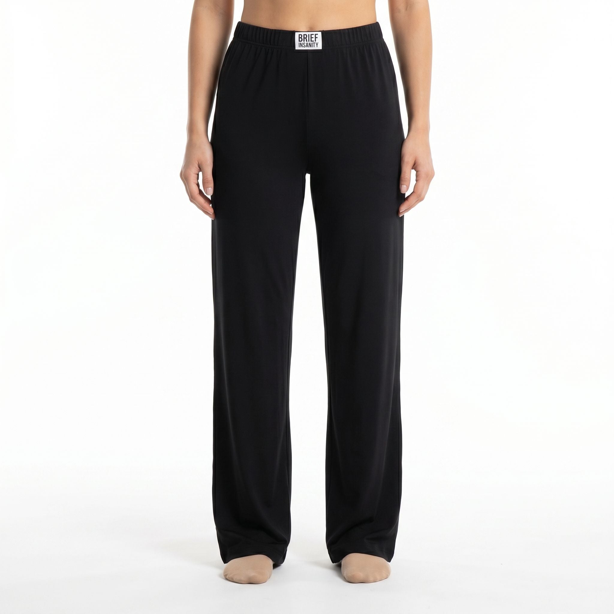Model wearing solid black lounge pants cropped from waist to ankles against a white background, showcasing the relaxed fit and fabric texture.