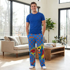 Male model wearing Superman logo lounge pants with a blue t-shirt in modern living room.